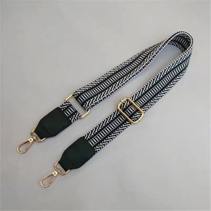 Close-up of black and white geometric woven bag strap with golden lobster clasps