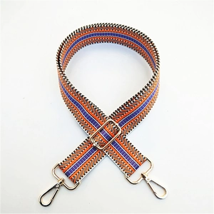 Macro detail of geometric patterned woven bag strap with golden lobster clasps