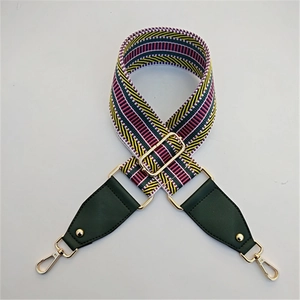 Détail de la bandoulière tissée à rayures avec bouts en cuir vert et crochets dorés