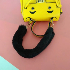 Détail d'un sac à main jaune en cuir avec sourire cartoon et anse en fausse fourrure