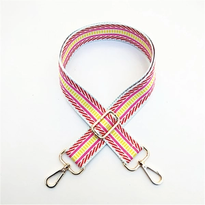 Detail of adjustable wide bag strap with pink and yellow geometric stripes and gold buckles