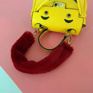 Détail de la poignée en fausse fourrure rouge et sac jaune avec fermoir rotatif en métal