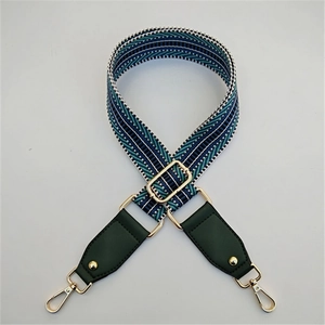 Detail view of woven bag strap with blue and green geometric patterns and gold clips