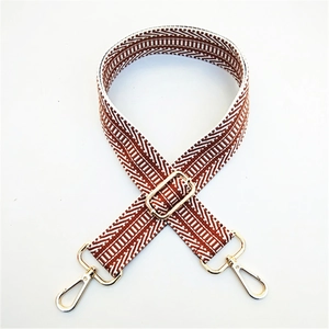 Detail of adjustable wide bag strap with red and white geometric woven wave patterns