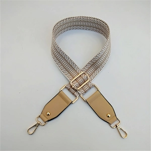 Detail of adjustable woven handbag strap with beige zigzag pattern and gold-tone hardware