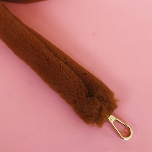 Détail de la bandoulière en fausse fourrure marron avec mousqueton en métal doré brillant
