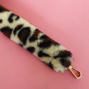 Détail d'une bandoulière en fausse fourrure léopard avec fermoir mousqueton doré