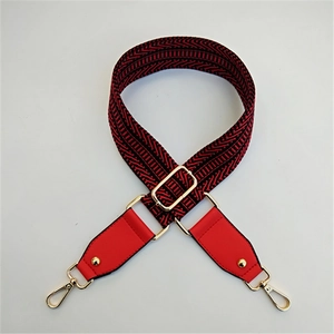 Detail of red and black geometric wave pattern wide bag strap with gold metal buckle