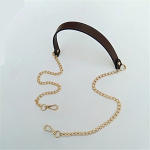 Detail of brown PU leather shoulder strap with golden metal chains and lobster clasps