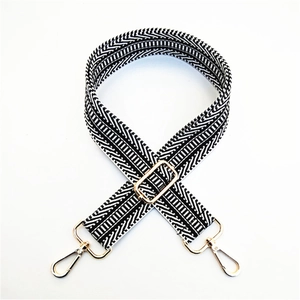Detail of black and white woven bag strap with golden metal clasp and adjustable buckle