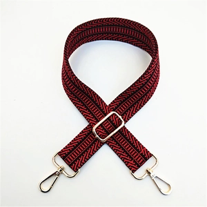 Close-up of adjustable wide strap with red and black geometric wave patterns and gold buckles
