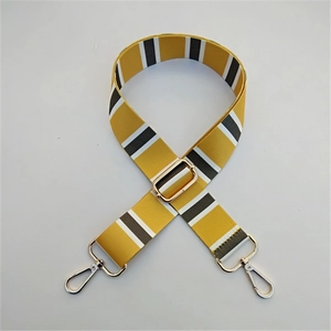 Detail view of adjustable mustard yellow nylon bag strap with striped pattern and silver buckle
