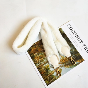 Detail of soft cream faux fur shoulder strap with golden metal clasps and leather trim