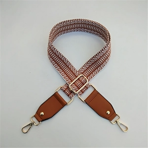 Close-up of brown and white geometric woven strap with golden metal lobster clasps