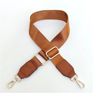Close-up of brown nylon bag strap with golden metal swivel hooks and adjustable buckle