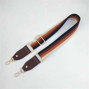 Detail of adjustable boho striped woven bag strap with leather ends and gold metal clips