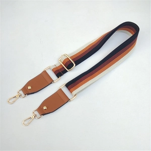 Detail of adjustable wide woven shoulder strap with orange stripes and gold metal hooks