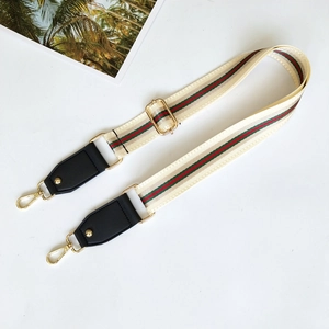 Detail of adjustable cream strap with red-green stripes and gold metal hardware