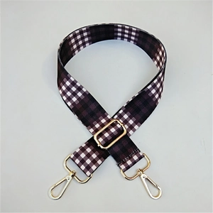 Close-up of black and white checkered canvas bag strap with golden metal hook and buckle