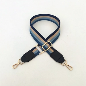 Detail view of ethnic adjustable wide bag strap with blue stripes and gold metal hardware