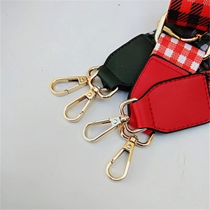 Detail of adjustable wide shoulder strap with red leather end and golden swivel hook hardware