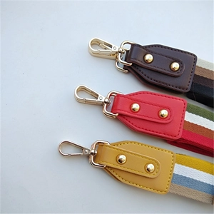 Detail view of woven striped bag straps with leather ends and gold metal clasps