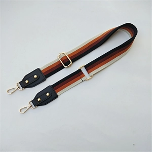 Macro detail of adjustable ethnic striped bag strap with gold metal hooks and leather