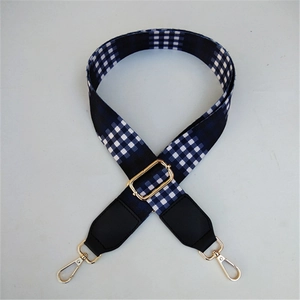 Close-up of navy blue and white checkered adjustable guitar-style strap with gold hooks