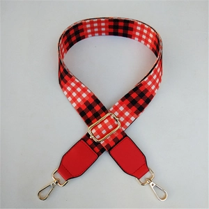 Detail of red and black buffalo plaid replacement bag strap with golden metal buckles