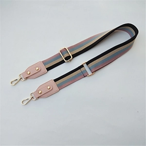 Close-up of ethnic striped woven bag strap with golden metal hooks and pink leather accents
