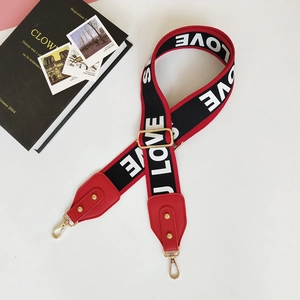 Détail de la bandoulière rouge et noire avec motif LOVE et crochets en métal doré