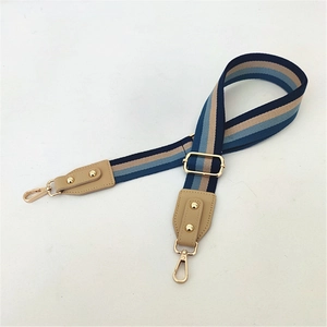 Detail of adjustable woven wide bag strap with navy stripes and light gold metal hardware