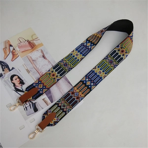 Close-up of ethnic geometric woven strap with gold metal hooks and brown leather ends