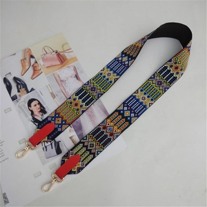 Close-up of ethnic geometric embroidered wide shoulder strap with gold metal buckles