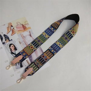 Detail of wide embroidered ethnic style bag strap with pink leather ends and gold hooks