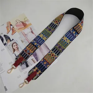 Close-up of ethnic style woven bag strap with red leather ends and gold metal buckles