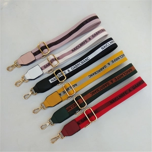 Detail of adjustable wide woven bag straps with gold metal hooks and luxury lettering