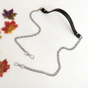 Detail of black leather handle with silver metal chain and lobster clasps for bags