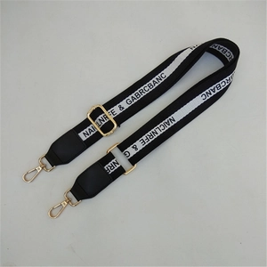 Detail of adjustable black and white crossbody strap with gold metal hooks and lettering