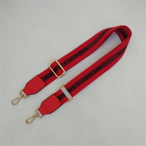 Detail view of red adjustable replacement bag strap with gold hooks and artistic patterns