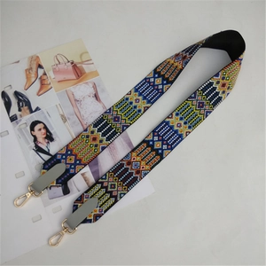 Close-up of ethnic style embroidered bag strap with geometric patterns and gold lobster hooks