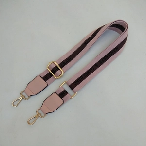 Detail of adjustable pink canvas strap with gold metal hooks and luxury woven patterns