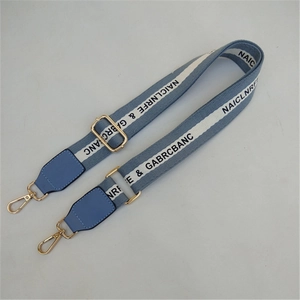 Detail view of adjustable light blue woven shoulder strap with gold metal hooks and leather trim