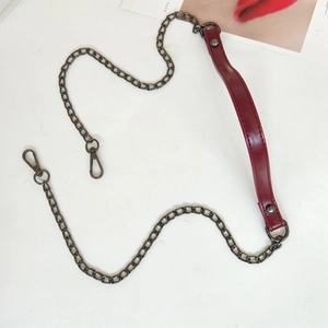 Macro detail of wine red leather shoulder pad and dark grey metal chain with lobster clasps