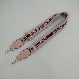 Macro shot of adjustable pink nylon strap with gold buckles and brown lettering detail