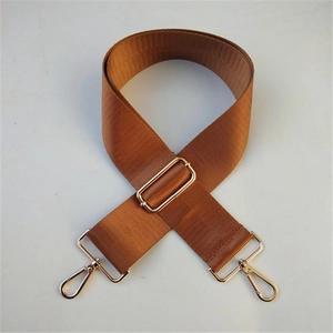 Dettaglio tracolla larga in nylon marrone con ganci e fibbie in metallo dorato