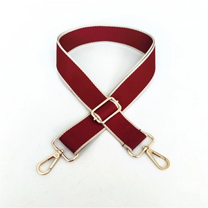 Detail of red and white striped wide bag strap with polished gold-tone metal clasps