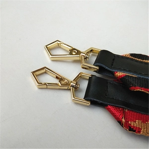 Détail de la bandoulière léopard rouge et or avec crochets dorés et finitions en cuir noir