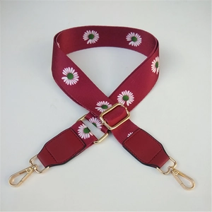 Detail of adjustable wine red bag strap with daisy print and golden metal buckles