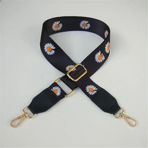 Detail of black nylon camera strap with white daisy pattern and gold metal hooks